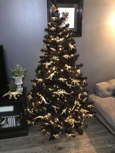 a black christmas tree with white lights in a living room next to a framed picture