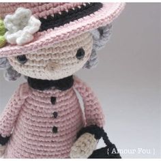 a crocheted doll wearing a pink dress and hat