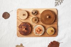 a wooden board with different types of candles and leaves on it, next to an oak leaf