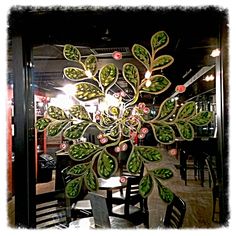 a glass window with green leaves and flowers on it's side in a restaurant