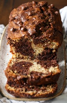 a loaf of chocolate chip banana bread on a white plate with a striped towel and napkin