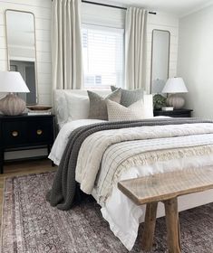 a bed with white sheets and pillows on top of it next to a wooden table