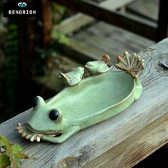 a frog figurine sitting on top of a wooden bench