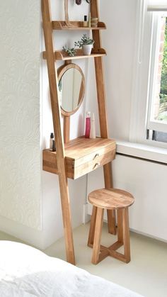 a wooden ladder is next to a mirror and stool in a room with white walls