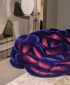 a large purple pillow sitting on top of a white floor next to a lamp and mirror