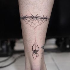 a spider web tattoo on the leg of a person's foot with barbed wire