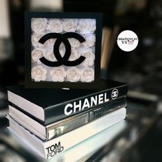 books stacked on top of each other in front of a chanel logo sign made out of roses