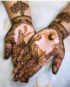 two hands with henna designs on them, one is holding an object in the other hand