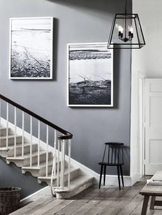 two pictures hang on the wall next to a stair case in a living room with wood flooring