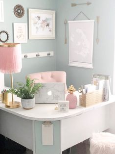 a white desk topped with a laptop computer sitting on top of a wooden table next to a pink chair