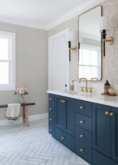 a large bathroom with blue cabinets and gold handles on the vanity, along with a white tiled floor