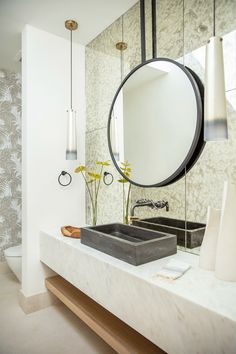 a bathroom with a sink, mirror and vase on the counter in front of it