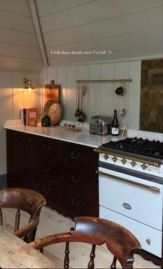 a kitchen with an oven, stove and chairs in it's center island area