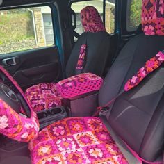 the interior of a car with pink and red crocheted seat covers on it