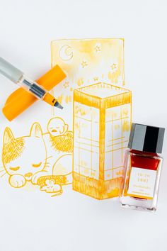 an orange ink pen next to a drawing of a cat and a box with a kitten on it