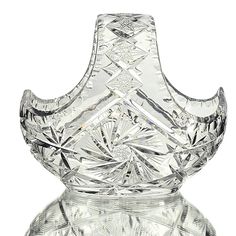 a clear glass vase sitting on top of a white tableclothed surface with an intricate design