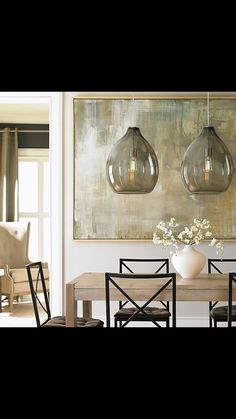 a dining room table with four chairs and a vase on the table in front of it