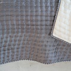 a close up of a bed with a gray and white comforter on top of it