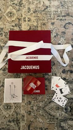 the contents of a card game laid out on top of a carpeted floor with white ribbons