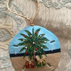 a ceramic ornament with a palm tree and presents on the beach in front of it