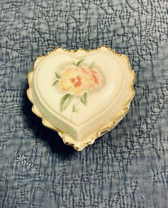 a heart shaped trinket sitting on top of a blue cloth covered tablecloth