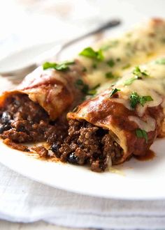 a white plate topped with lasagna covered in meat and cheese