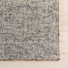 an area rug on top of a wooden floor with white and gray colors, including black dots