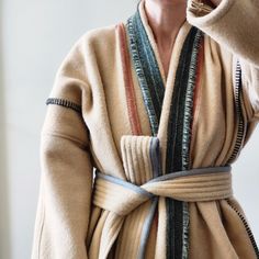 "This one of a kind wool robe, wrap coat is made from fabric remnants sourced from a U.S. heritage woolen mill. The body features a muted pink napped wool accented with graphite blanket stitch, marled moss panel down the center back, marled racing green shawl collar, and dove grey binding on the quilted belt. The belt is detachable if the wearer would prefer to style as a duster coat, body is unlined with no stretch, side seam pockets in marled forest green wool.  Body is approximately 32\" wide/across from shoulder seam down to hem.  Sleeves are approximately 16\" long from shoulder seam to cuff. Suggested to fit a size women's M to L. *Wearer in photo is 5'2\" and typically wears a size small in outerwear." Beige Wool Shawl Collar Outerwear, Winter Cashmere Wrap Outerwear, Wool Wrap Outerwear For Fall, Moss Panel, Wool Robe, Wool Duster, Wool Blanket Coat, Quilted Robe, Green Shawl