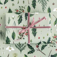 two wrapped presents tied with pink ribbon on top of green and white christmas wrapping paper