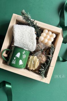 a box filled with coffee, marshmallows and other holiday treats next to a green ribbon