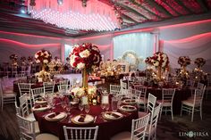 a room filled with lots of tables covered in white and red flowers