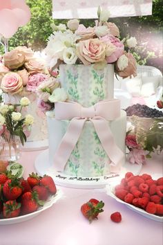 a three tiered cake sitting on top of a table next to plates of strawberries