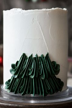 a white cake decorated with green icing and a christmas tree decoration on the top