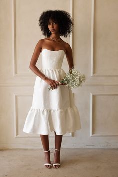 a woman in a white dress holding flowers