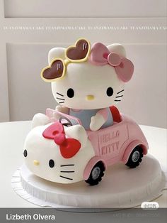 a hello kitty cake with sunglasses on top and a pink car in the shape of a cat