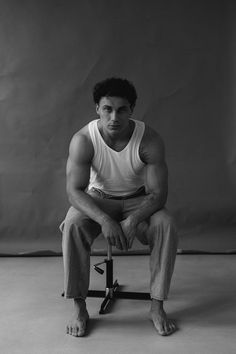 a black and white photo of a man sitting on a stool