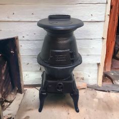 an old fashioned black stove sitting in front of a white building with wood and siding