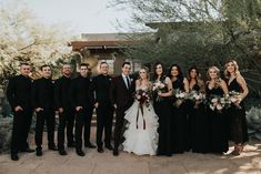 a group of people standing next to each other in front of some trees and bushes