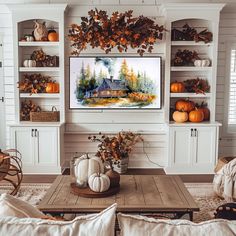 a living room filled with white furniture and fall decorations on the wall above a flat screen tv