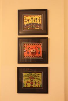 three framed pictures hang on the wall above a toilet