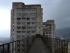 a very tall building with lots of windows on it's sides and a walkway leading up to the top