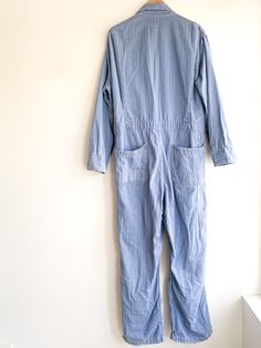 Periwinkle blue coveralls with laurel wreath donut hole buttons. Style with a belt for a slouchy oversize look. Fabric: CottonLabel: PeerlessFit: M/LEra: 1930/40's Measurements: Bust 45" Shoulder 19.5" Sleeve 23.5" Waist 38" Hips 44" Rise (from neck) 32" Inseam 29" Length 63" Leg opening 10" Condition: Very good. A few small holes throughout and some fraying on pant cuffs (see photos). Fitted Vintage Denim Jumpsuit For Work, Vintage Fitted Denim Jumpsuit For Work, Retro Long Sleeve Overalls For Work, Vintage Denim Jumpsuit For Work, Vintage Cotton Jumpsuits And Rompers With Relaxed Fit, Vintage Cotton Jumpsuits And Rompers In Relaxed Fit, Vintage Denim Overalls Jumpsuit In Relaxed Fit, Vintage Jumpsuits And Rompers With Pockets In Relaxed Fit, Vintage Long Sleeve Overalls For Spring