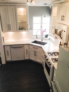 a kitchen with white cabinets and wood floors