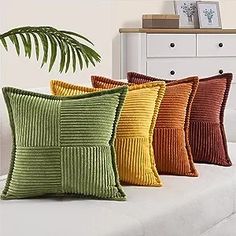 four different colored pillows sitting on top of a white couch next to a potted plant