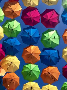 many multicolored umbrellas are hanging in the air together on a sunny day