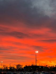 a parking lot filled with lots of parked cars under a red and orange sky at night