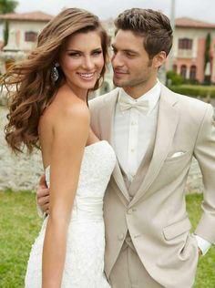 a man and woman in formal wear standing next to each other on the grass with their arms around each other