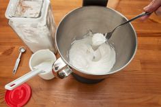 a person mixing white batter in a metal bowl