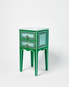 a small green table with two drawers on each side and an ornate design on the top