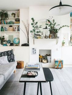 a living room filled with furniture and a fire place next to a wall mounted book shelf